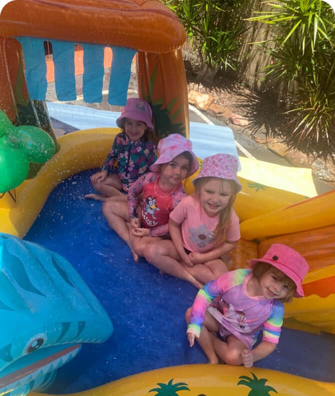 four small girls playing around on a slide